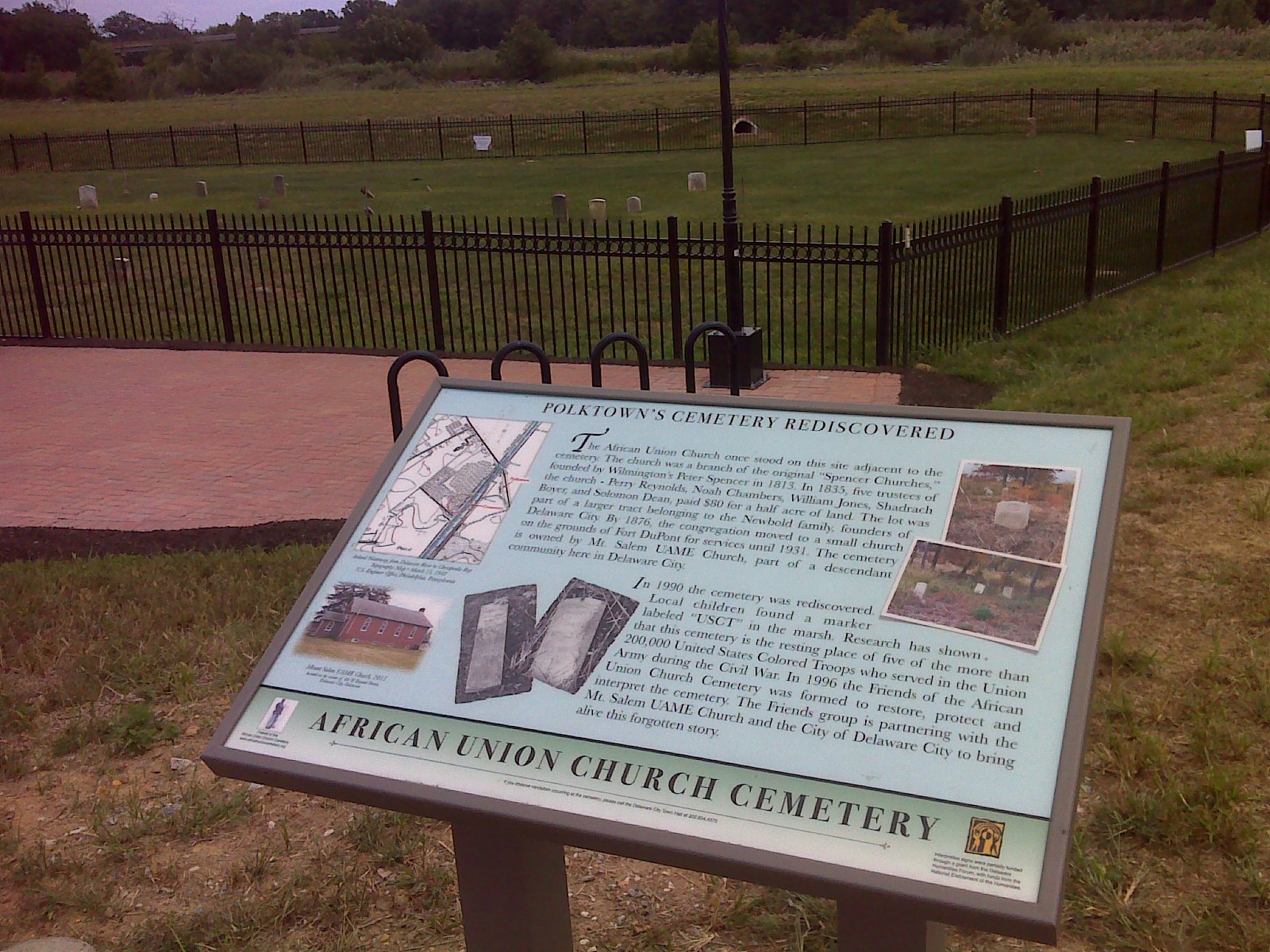 African Union Church Cemetery interpretive sign beside the brick memorial plaza and fenced burial ground