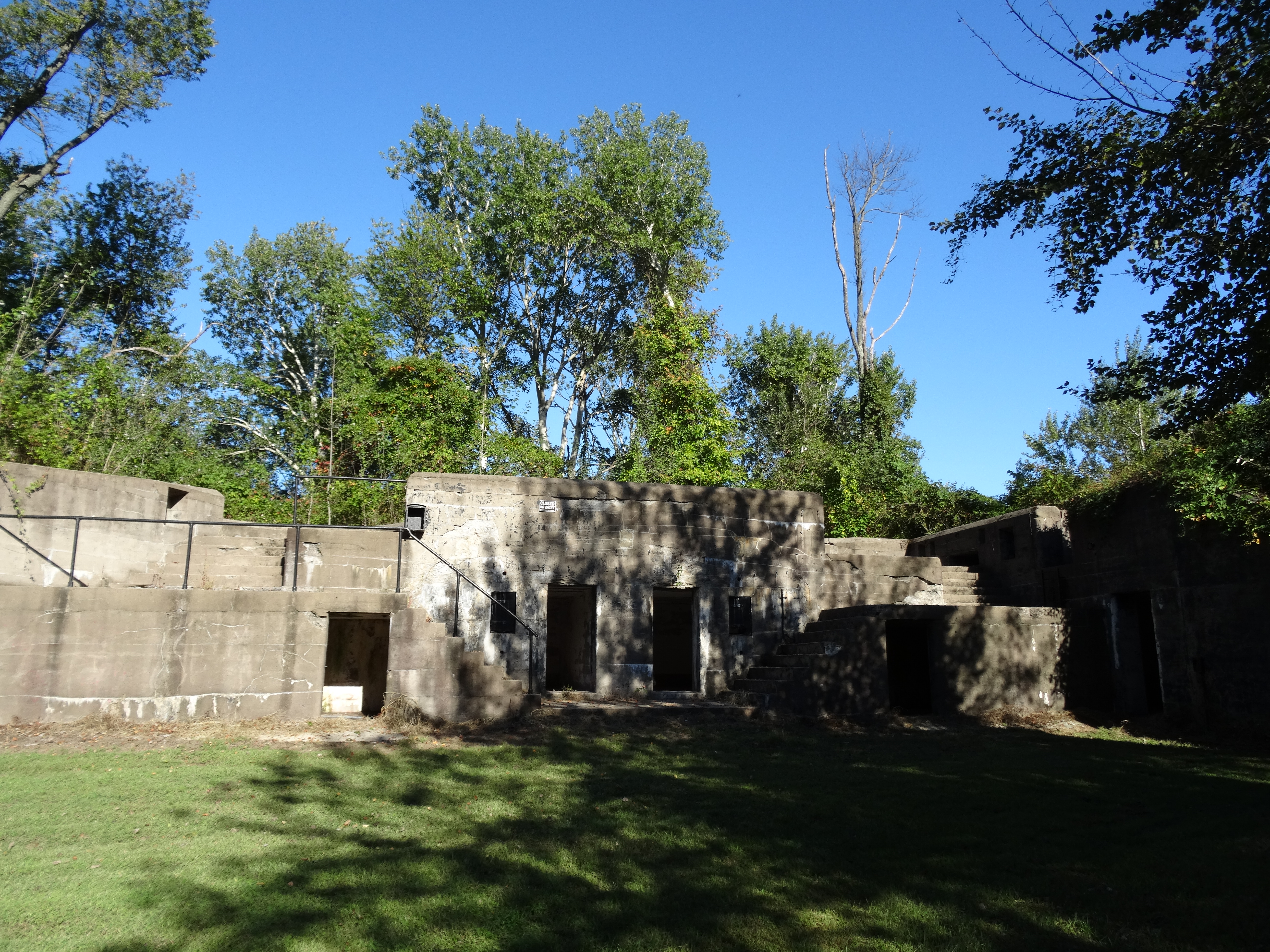 Historic concrete gun-battery ruins amid trees and grass at Fort DuPont