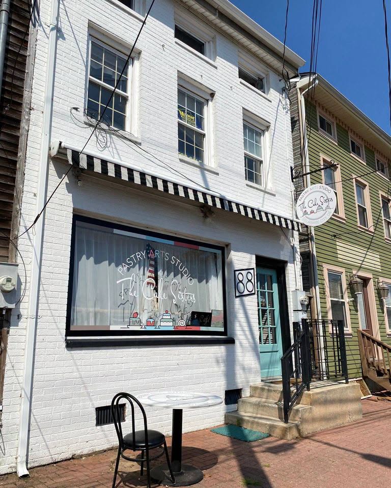 A white-brick downtown building with an awning and outdoor seating