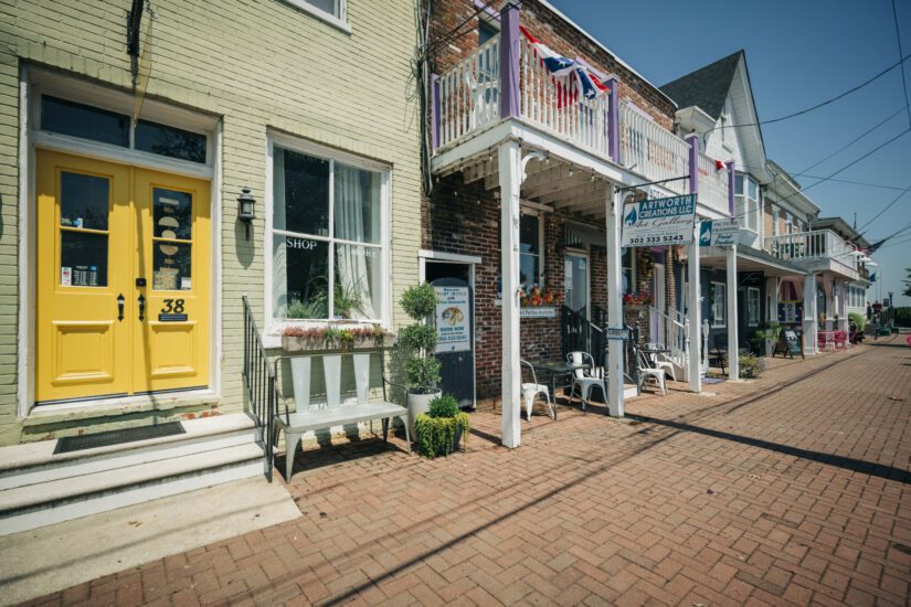 Clinton Street storefronts with a yellow door, covered porches and a brick sidewalk