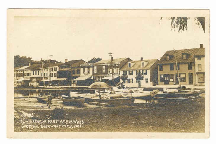 Sepia postcard of boats moored beside Delaware City’s waterfront businesses