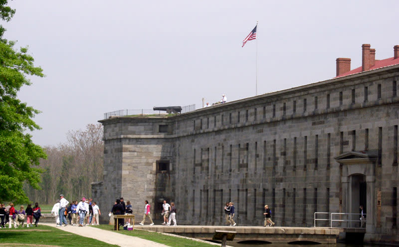 Visitors crossing the bridge beside Fort Delaware’s stone walls and moat