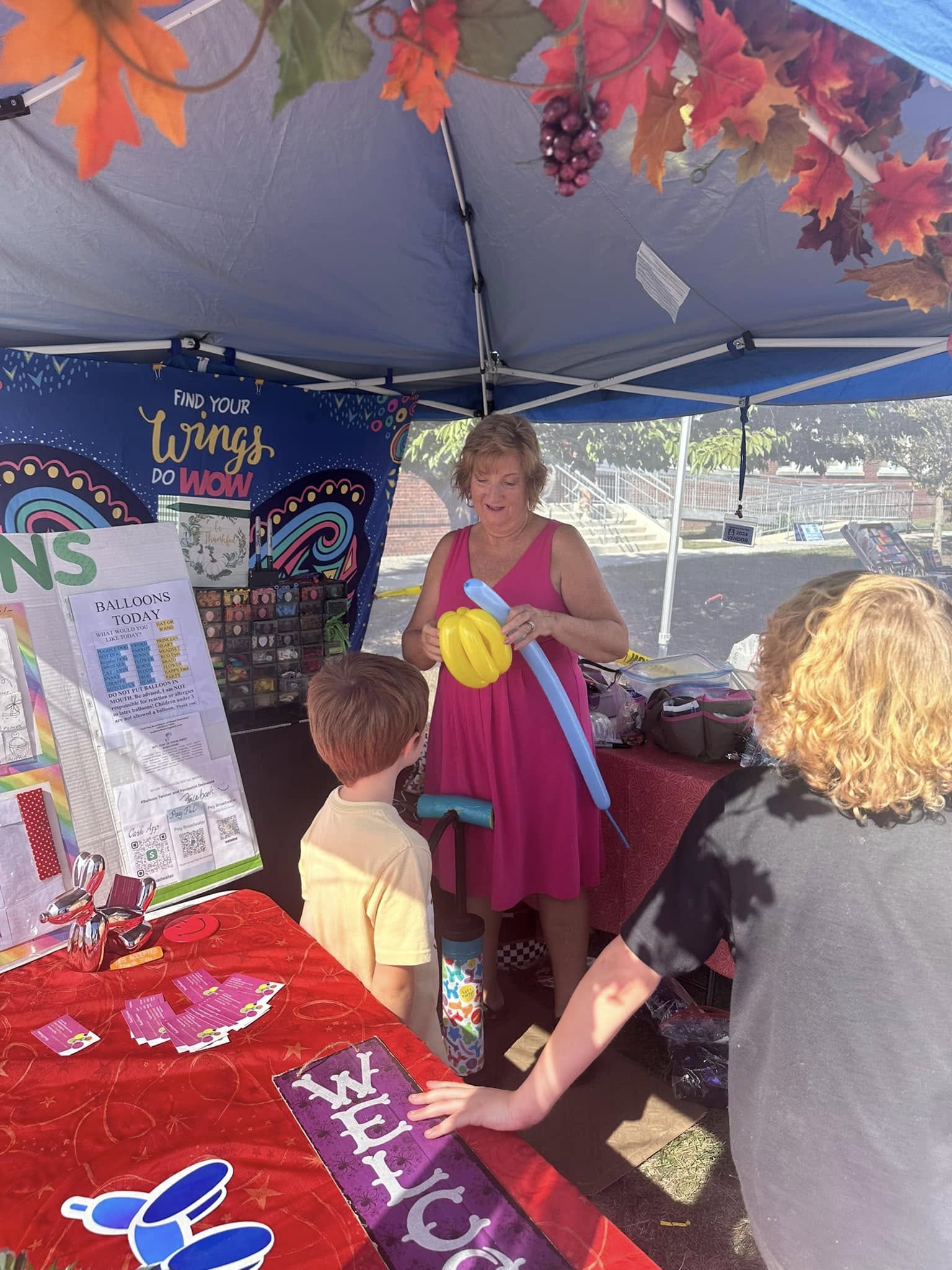 A balloon artist holding finished balloon creations for a child