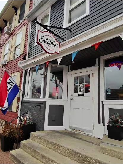 Sabatina’s storefront with its hanging sign, white entrance door and steps on Clinton Street
