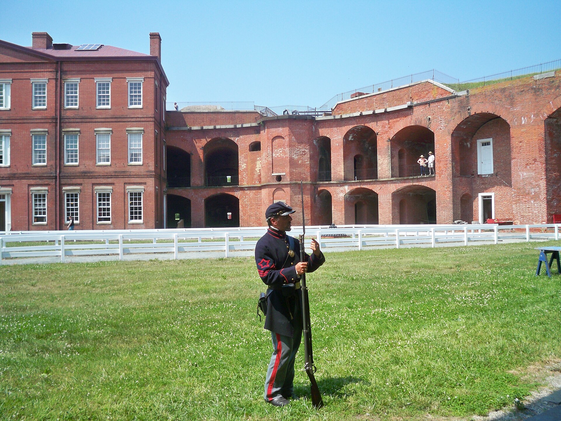 Uniformed living-history soldier holding a musket in the Fort Delaware courtyard