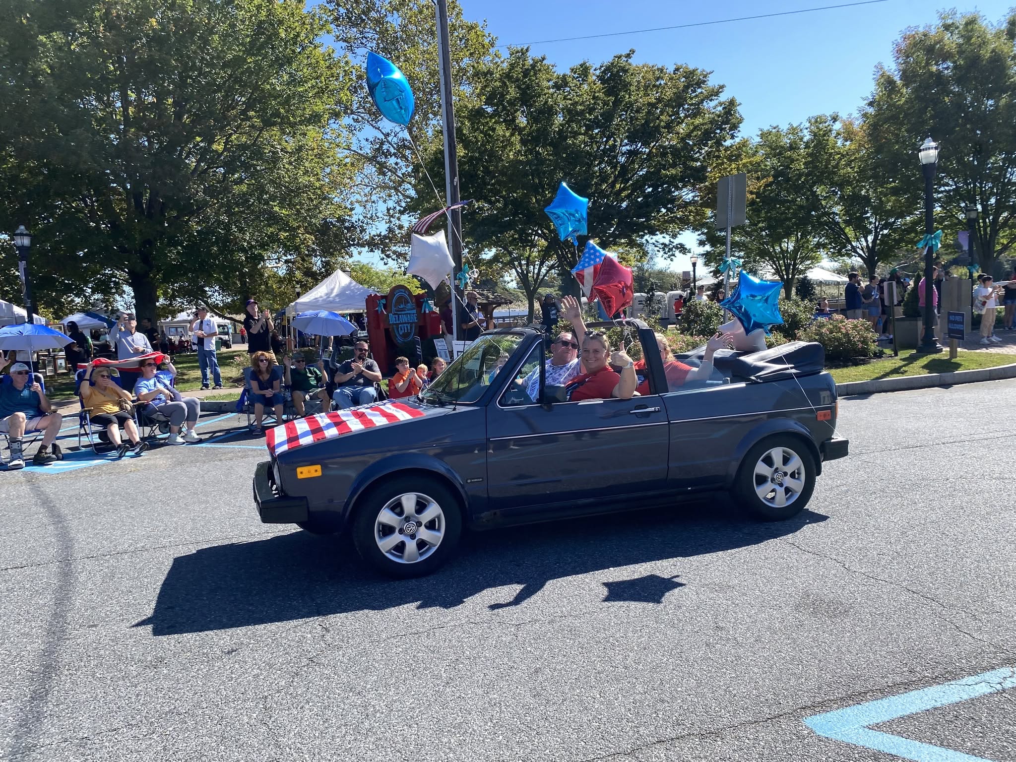 A convertible decorated with balloons driving in the parade