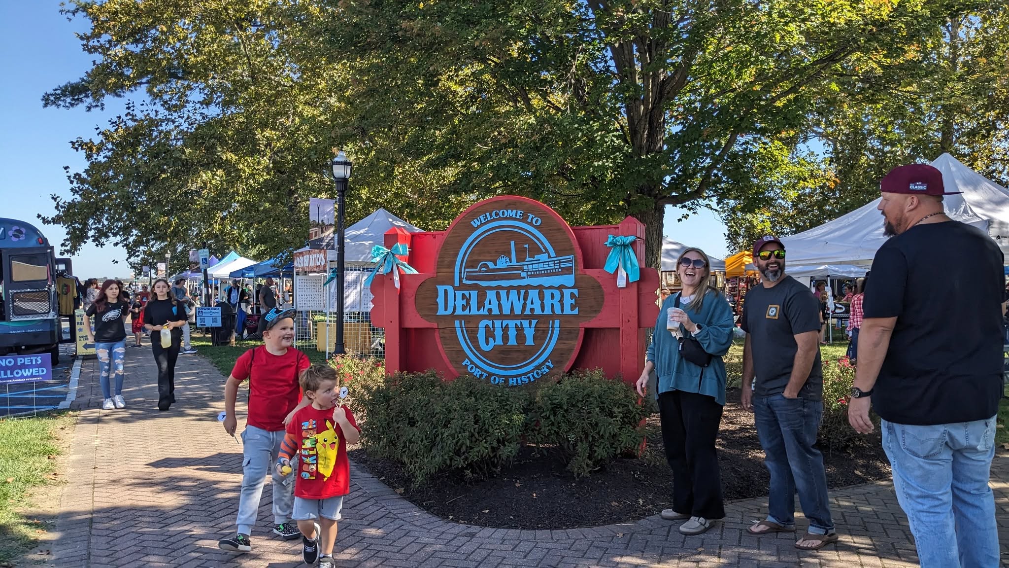 Attendees walking past the wooden Delaware City entrance sign