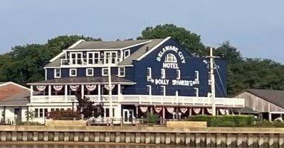 Historic waterfront building along the canal with flags and a small boat