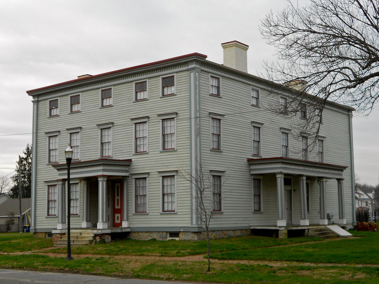 Light grey clapboard house on Washington Street with columned porches and brick chimneys