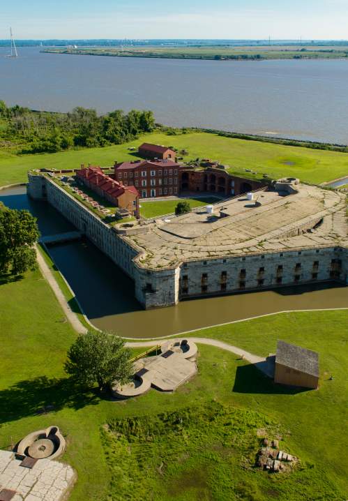 Aerial view of Fort Delaware’s stone walls and moat, red-roofed buildings, island lawns and the Delaware River