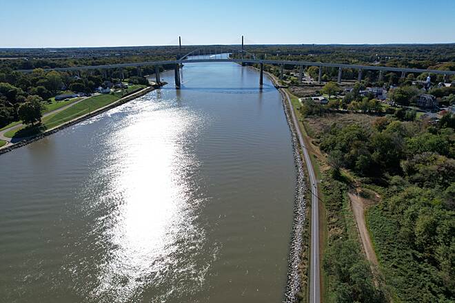 Aerial view along the C&D Canal with a paved shoreline trail and bridges in the distance