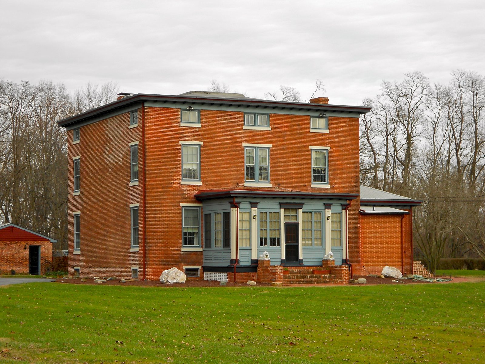 Cubic red-brick house with a low-pitched roof, bracketed cornice and an enclosed front porch