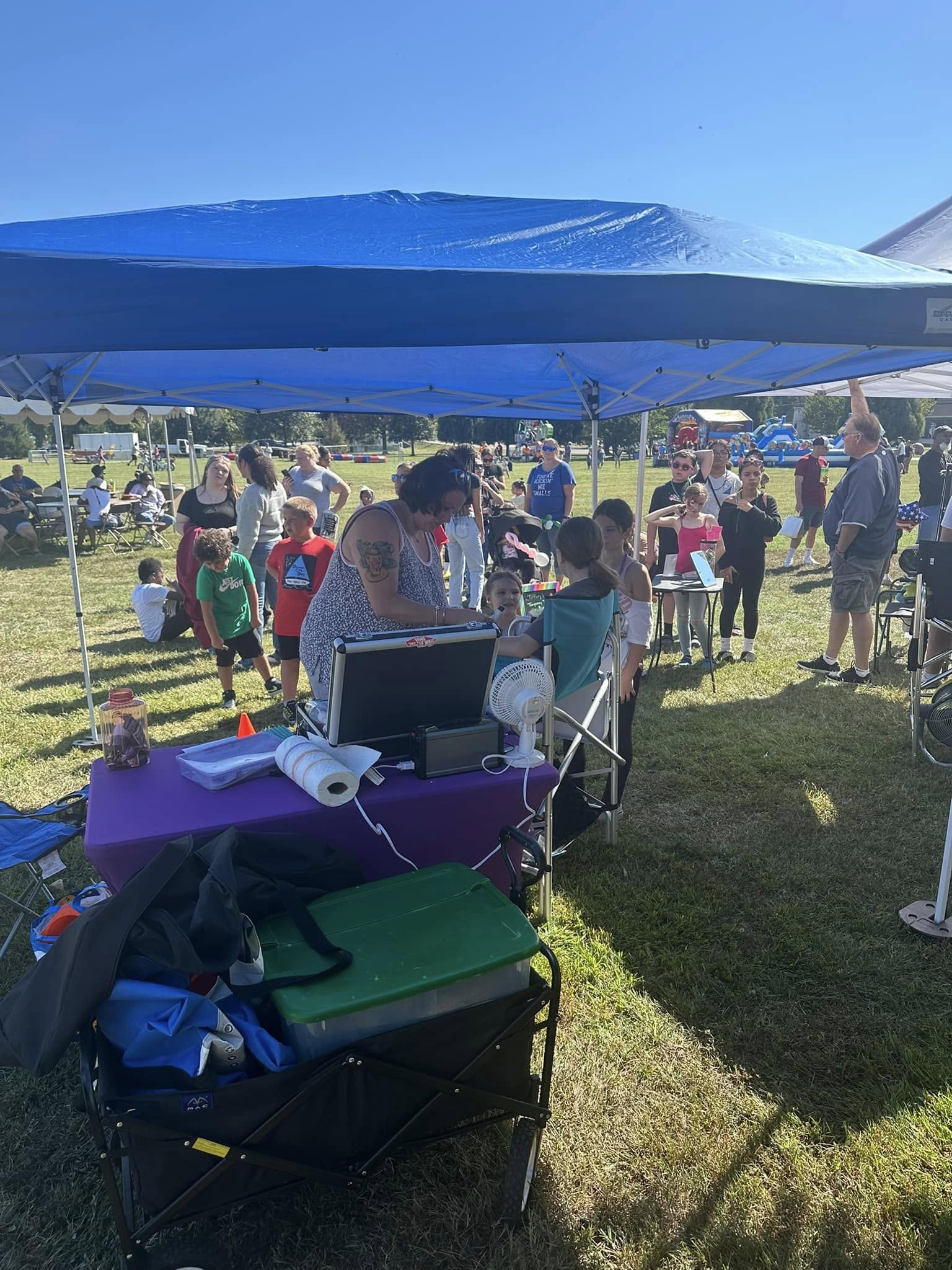 Sound and lighting equipment under a canopy with attendees gathered nearby